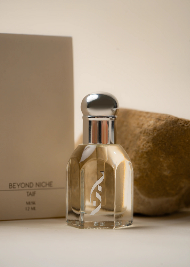 A small bottle of golden oil resting against its boxes