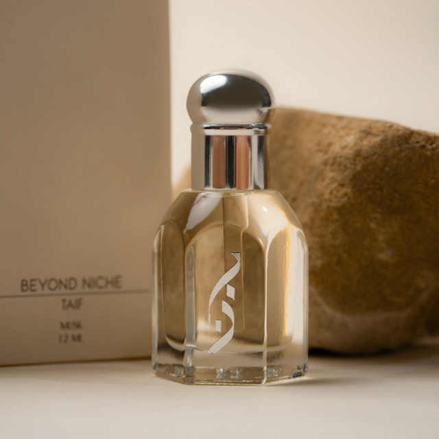 The Taif oil bottle in front of its box, a desert stone behind